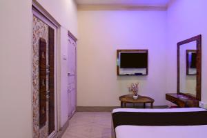 Una habitación con un espejo y un televisor en la pared. en Hotel O Vedika, en Calcuta 33 fotos más