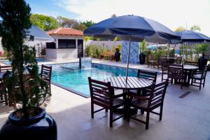 un patio con tavoli e ombrelloni accanto alla piscina di Hotel & Pousada Porto Ubá a Lidianópolis