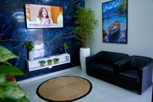 un soggiorno con sedia nera e TV di Hotel & Pousada Porto Ubá a Lidianópolis
