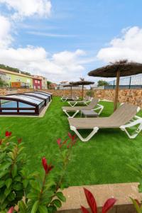 a group of lounge chairs and umbrellas on a lawn at Casa El Rincón de Alberto con Piscina CLIMATIZADA y Calefacción in Camelle
