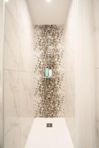 ein Bad mit einer Dusche und einer Steinmauer in der Unterkunft Les Maisons Bareyre - Grandes Maisons avec terrasse in Saint-Sandoux