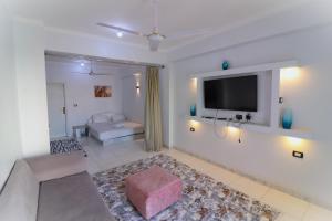 a living room with a couch and a tv on a wall at Mama Africa Apts & Studios in Luxor