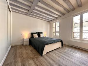 Un dormitorio con una cama grande y dos ventanas. en Évasion sur la rivière - 4 pers - Centre, en Moret-sur-Loing