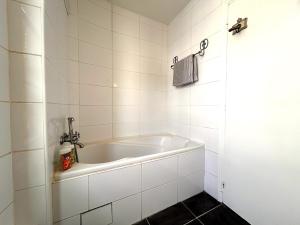 Una bañera blanca en un baño con azulejos blancos. en Évasion sur la rivière - 4 pers - Centre, en Moret-sur-Loing