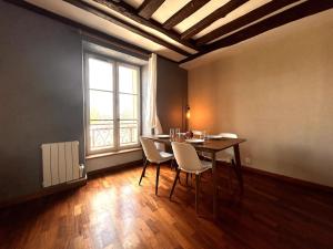 Un comedor con mesa y sillas y una ventana. en Évasion sur la rivière - 4 pers - Centre, en Moret-sur-Loing