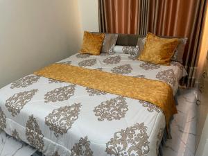 a bedroom with a bed with white and gray comforter at Jaffa Suites in Kampala