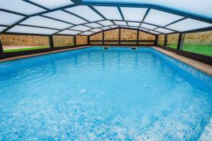 a large swimming pool with a large roof at Casa El Rincón de Alberto con Piscina CLIMATIZADA y Calefacción in Camelle