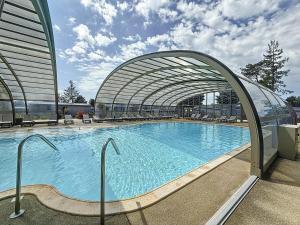a large swimming pool in a building with an archway at Cottage Le Béluga in Jullouville-les-Pins