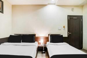 a room with two beds and a desk with a door at Super Collection O Sindhi Camp Formerly Hotel Abhinandan Inn in Jaipur