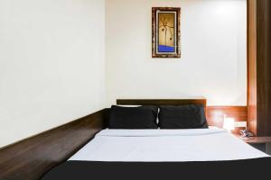 a bedroom with a bed with white sheets and a mirror at Super Collection O Sindhi Camp Formerly Hotel Abhinandan Inn in Jaipur