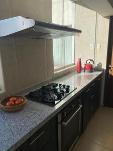 a kitchen with a stove and a bowl of fruit on the counter at Departamento amoblado para Convención Minera - Perumin in Arequipa