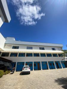 a white building with a car parked in front of it at Pousada Vilela in São Mateus