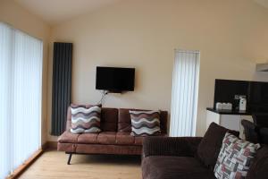 ein Wohnzimmer mit Couch und Flachbildfernseher in der Unterkunft Loch Ness Highland Cottages with partial Loch View in Invermoriston