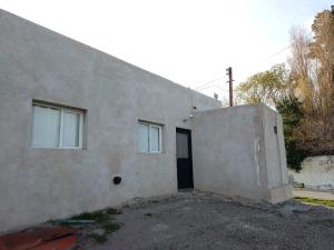 un edificio blanco con una puerta y dos ventanas en El Rincón de km8, en Comodoro Rivadavia