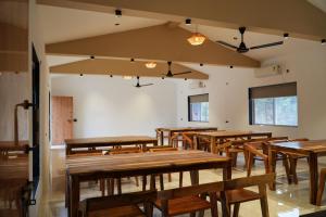 a dining room with wooden tables and chairs at Vrindaa- The Bliss Retreat in Karjat
