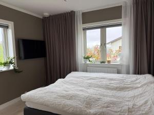 Un dormitorio con una cama blanca y dos ventanas. en Fantastic villa with pool near Stockholm, en Estocolmo 51 fotos más