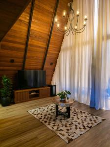 Una sala de estar con una mesa y un televisor. en Gran Chalé, en Santa Teresa