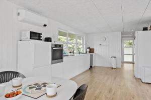 a white kitchen with a table and a refrigerator at JB318-Fjerritslev-Fiskerstien-10 in Torup Strand +22 photos