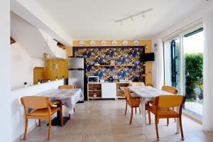 a kitchen with two tables and chairs and a refrigerator at B&B Ruota di Carretto in Nicolosi