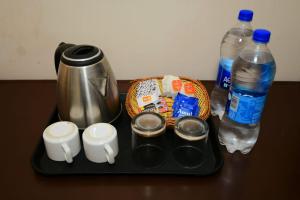 a tray with a coffee pot and two bottles of water at Ds Royal Inn in Malhour