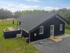 a black tiny house with a porch and a deck at Holiday Home Holke - 600m from the sea by Interhome in Hirtshals
