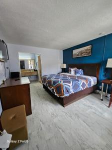 a bedroom with a bed and a blue wall at Rodeway Inn Hattiesburg North in Hattiesburg