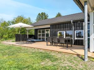 une terrasse avec des chaises et un parasol sur une maison dans l'établissement Holiday Home Nayati - 2km from the sea by Interhome, à Saltum