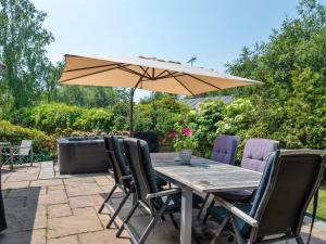 a wooden table with chairs and an umbrella at Holiday Home Elline - 450m from the sea by Interhome in Græsted