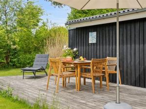 a wooden table with chairs and an umbrella on a deck at Holiday Home Ilsabet - 750m from the sea by Interhome in Gilleleje