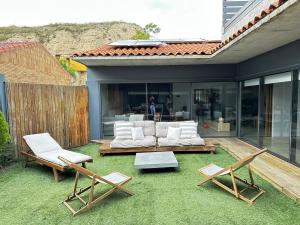 a patio with a couch and two chairs on the grass at Casa Tilin in Valtierra