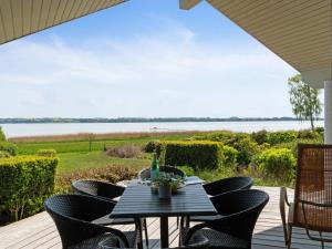 una mesa y sillas en una terraza con vistas al agua en Holiday Home Brunman - 10m to the fjord by Interhome, en Grevinge