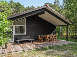 a black house with a wooden deck with a table and chairs at Holiday Home Efka - 175m from the sea by Interhome in Asnæs