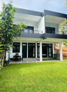 a white house with a green lawn in front of it at Villa Green View in Hikkaduwa