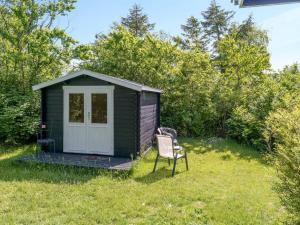 a small black shed with a chair in the grass at Holiday Home Gærmund - 350m from the sea by Interhome in Føllenslev