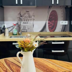 a white vase with flowers sitting on a table at Lope 20 - Apartamento céntrico y tranquilo in Jaén +6 photos