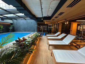 einen Pool mit Liegestühlen und Pflanzen in einem Gebäude in der Unterkunft Boulevard Vistula Apartment Swimming Pool, Sauna, Gym & Parking in Krakau
