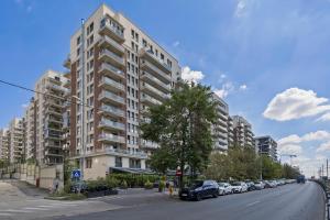 een groot gebouw met auto's geparkeerd aan de kant van een straat bij Terracotta Oasis in Boekarest