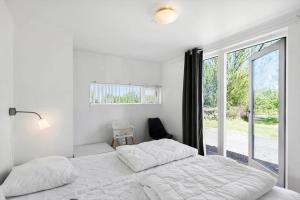 ein weißes Schlafzimmer mit einem Bett und einem Fenster in der Unterkunft JB328 Brovst - Kronvildtvej 184 in Tranum