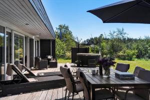 eine Terrasse mit Tisch und Stühlen und einem Sonnenschirm in der Unterkunft JB328 Brovst - Kronvildtvej 184 in Tranum
