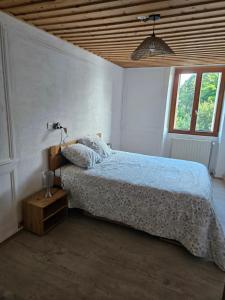 a bedroom with a bed and a lamp and a window at Le moulinot in Morteau