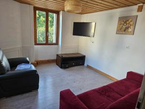 Una sala de estar con un sofá y un televisor de pantalla plana. en Le moulinot, en Morteau