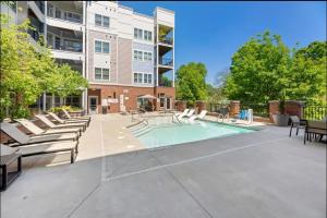 a swimming pool with lounge chairs and a building at Stylish 1BR Uptown Apartment in Charlotte