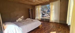 a bedroom with a bed and a large window at ecolodge San miguel in Tupiza