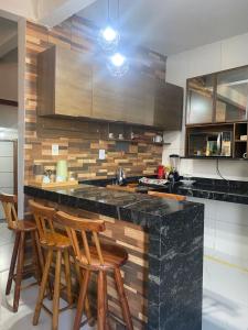 a kitchen with a black counter top and wooden stools at Villa Zilá in Vila Velha