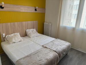 a bed with white sheets and pillows in a bedroom at Central Hôtel in Saint-Priest +7 photos