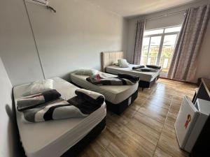 a room with three beds and a window at Hotel e Restaurante Santa Fé in Lages