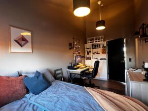 a bedroom with a bed and a desk and a kitchen at Home in the country in Hella