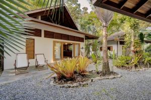 a house with a patio with two chairs and a tree at Bodhi & Nirvana Houses in Talamanca