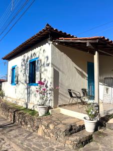 a white house with a table and chairs in front of it at Casa Donna Flor 2 Quartos Completa Centrinho com Garagem Coberta in Catas Altas