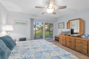 Gone Coastal l Ground Floor Condo l Steps to Beach في Anastasia Island: غرفة نوم بها سرير ومروحة سقف